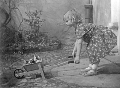 Pikkutyttö leikkii kottikärryillä. Valokuvaus noin 1931 tekijältä Unbekannt