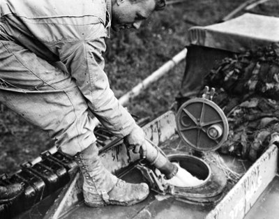 Toinen maailmansota (WWII) (1939-1945) - Toinen maailmansota (WWII tai WW2): Normandia (Ranska) Kesä 1944: Yhdysvaltalaisen kuljetusyrityksen sotilas tankkaa kaasun varastointiasemalla polttoainetta GMC-tankkerin tankkiin. tekijältä Unbekannt