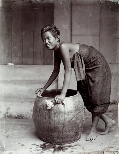 Nuori hymyilevä thaimaalainen nainen työntämässä suurta säiliötä. tekijältä Unknown photographer