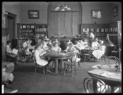 Lapset lukevat Queens Borough Public Libraryn tunnistamattoman haaran lukusalissa, n. 1910 tekijältä William Davis Hassler