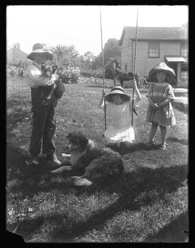Lapset koiran ja pennun kanssa kokoontuivat köysikeinujen ympärille McCready Farmilla Pennsylvaniassa, n. 1913 tekijältä William Davis Hassler