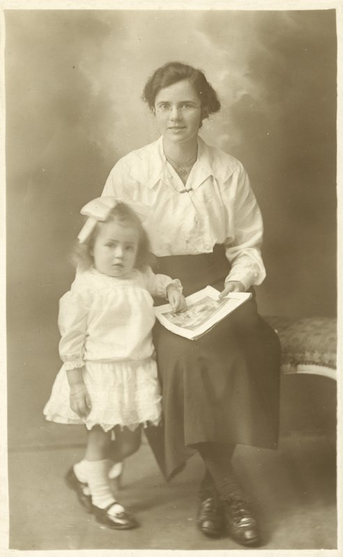 Nätti tyttö, äiti tai kasvatustytär, näyttää kuvia pienelle lapselle (m/w kuva) tekijältä English Photographer