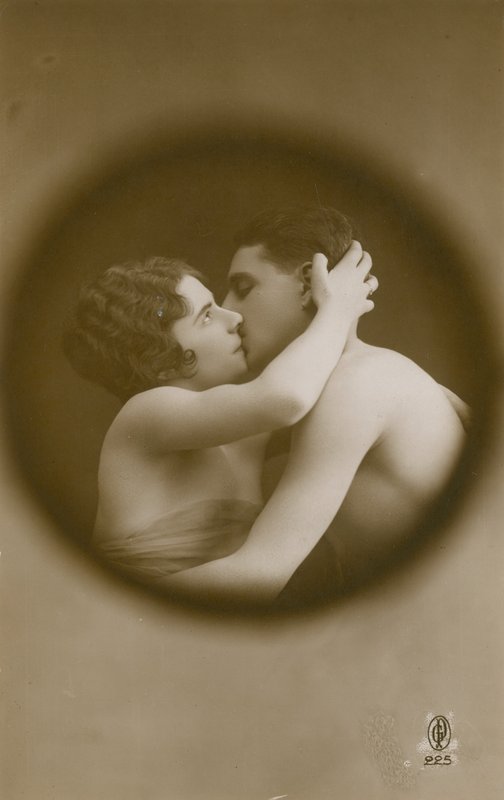 Nuori mies ja nainen suutelevat katselureiän läpi katsottuna. Postikortti lähetetty 1913. tekijältä French Photographer