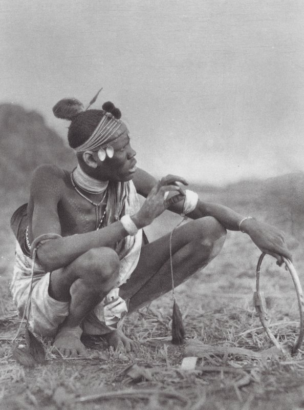 Afrikka: Dinka-sulhanen tinkii morsiuskoristeista (s/w-kuva). tekijältä Hugo Adolf Bernatzik