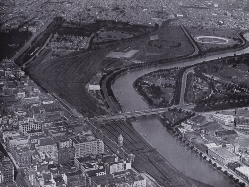Melbourne: Yarra-joen ja Jolimontin ratapihojen ilmakuva, jossa näkyy pieni osa kaupunkia ja Richmond kaukana (s/w-kuva). tekijältä Photographer Australian