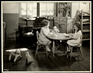 Kaksi sokeaa näkövammaista tyttöä syömässä pienen pöydän ääressä nuken kanssa New York Association for the Blindissa, 111 East 59th Street, New York, 1933 (hopeagelatiiniprintti)