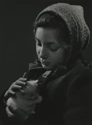 Tyttö pitää valkoista kissanpentua sylissään. 1950-luvun alku