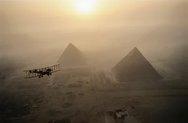 Vintage-lentokone Vimy lentää sumun peittämien pyramidien yläpuolella kultaisen auringonpaisteen aikana....