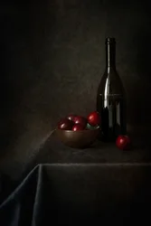 Asetelma, jossa on luumuja ja pullo