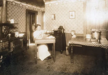 Nainen työntää harjaksia hammasharjoihin keittiössään, n. 1912