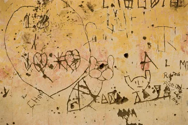 Grafitti, joka on kaiverrettu vanhaan ulkoseinään.
