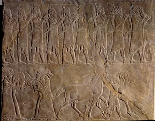 Ashurbanipalin armeijan muusikot. Matala kohokuvio kalkkikivessä noin 640 eKr. (uusassyrialainen kausi, v.1000-612 eKr.). Löytyi Mesopotamian Ninivestä. Louvren taidemuseo.