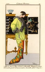 Nainen, jolla on silkkimekko, jossa on chinchilla-verhoilu, sitruunanvihreä samettiviitta, jossa on chinchilla-kaulus ja hihansuut, kädessään jade-buddha. Taustalla kiinalainen kaappi. Robe de soie de chine bordee de chinchilla, manteau de velours citron v