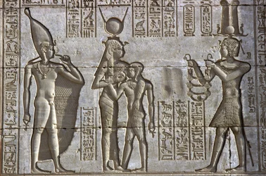 Muinainen Egypti, seinämaalaus/veistos, Isis imettää nuorta faaraota jumalallisen Ihy-lapsen läsnä ollessa, kun faarao tekee uhrilahjan, Hathorin temppeli, Dendera (kuva)