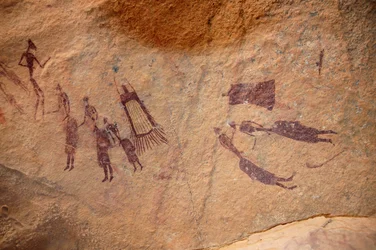 Kalliotaide, esihistoria: Kalliomaalaus ryhmästä hahmoja ja "guerbaja" (ulkopuolia) on hapsuja ja ilman hapsuja koristeellisessa suojassa Uweinatin ylängöllä, Sudanissa. Ajanjakso 8000-3000 vuotta eaa. Valokuvaus