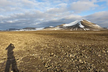 Ihmisen varjo, polygonimaata Platabergetillä, taustalla lumipeitteinen Nordenskjöldfjelletin huippu, lähellä Longyearbyeniä, Huippuvuoret, Svalbard, Norja, Eurooppa