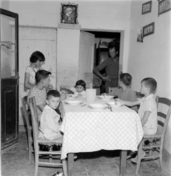 Suuri perhe kokoontui pöydän ääreen maalaistalon ruokasalissa. 1960-luku