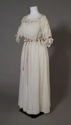 Bertha Palmerin yöpaita, n. 1880 (vinokuva edestä), valkoista puuvillaa, pitsiä, brodeerausta ja silkkinauhaa.