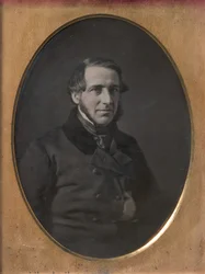 Keski-ikäinen mies, jolla on leukahihnaparta, käsin työnnetty nappitakki, 1840-50-luku