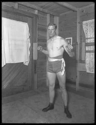 Englantilainen nyrkkeilijä William Thomas Wells (Bombardier Billy Wells), poseeraa harjoitushousuissa painopyörillä, n. 1911