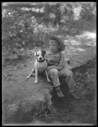William Gray Hassler olkihatuissa ja haalareissa, poseerasi metsässä pienen koiran (Bessie) kanssa, 20. elokuuta 1911