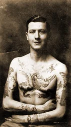 Muotokuva miehestä, jolla on taidokkaita tatuointeja, n. 1920